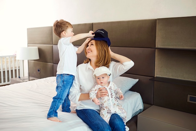 Avó com netos sentados na cama do quarto