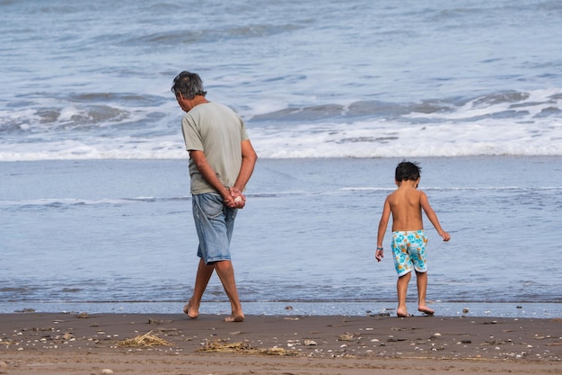 Avô com seu neto procurando caracóis na praia