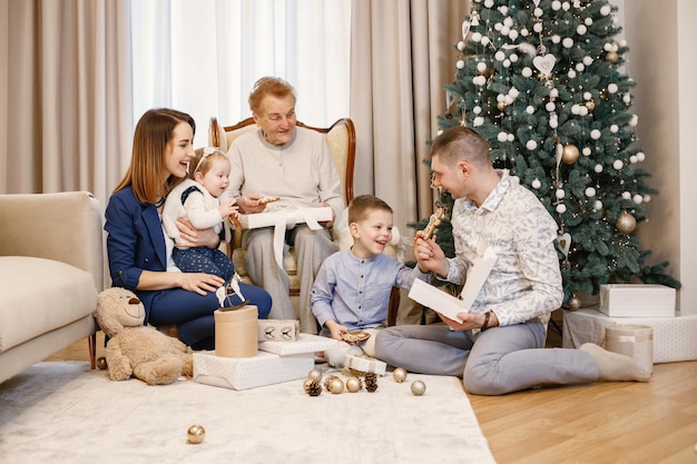 Avó com seus parentes sentados perto da árvore de natal