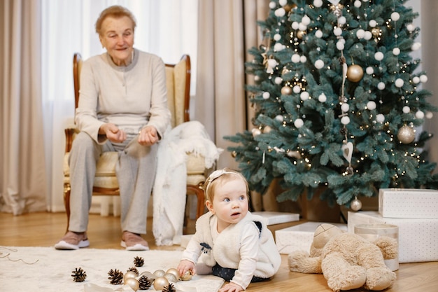 Avó com sua neta sentada perto da árvore de Natal