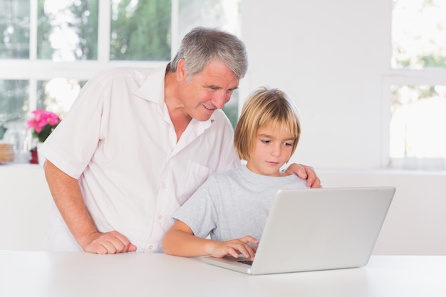 Avô e criança olhando laptop com sorriso