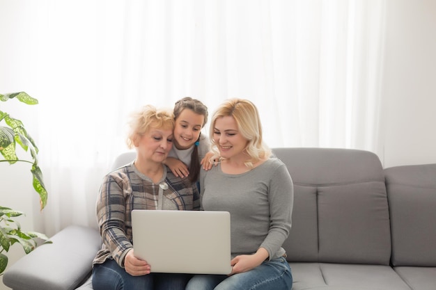 Avó e filha ensinando criança a usar o aplicativo do laptop, jogando