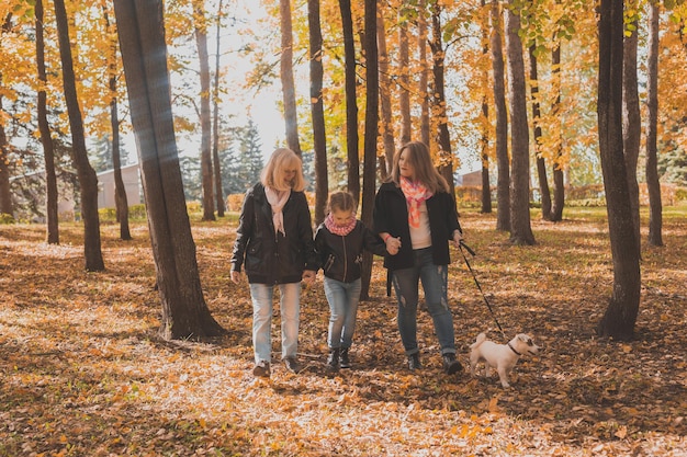 Avó e mãe com a neta caminham juntas no parque outono e se divertem geração