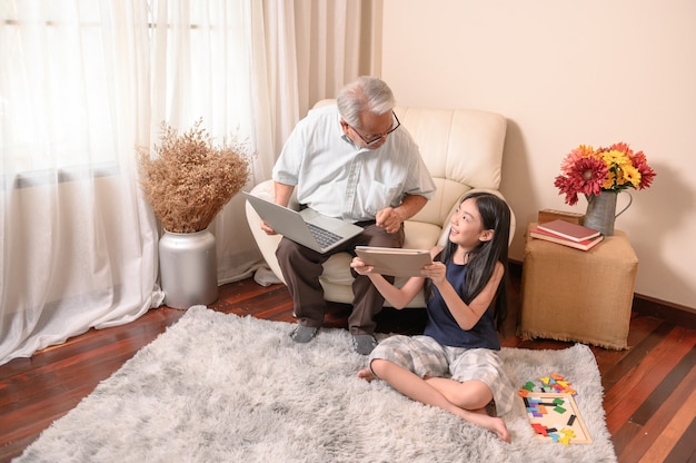 Avô e neta aprendendo online em casa. Estilo de vida em idade de aposentadoria com a família nas férias de verão.