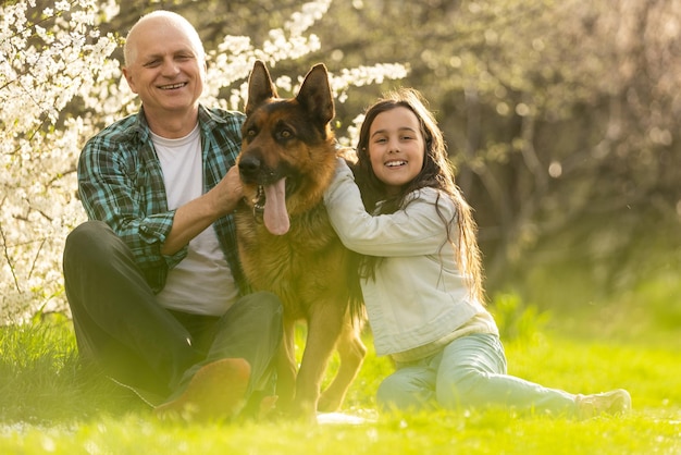 Avô e neta com cão pastor no jardim