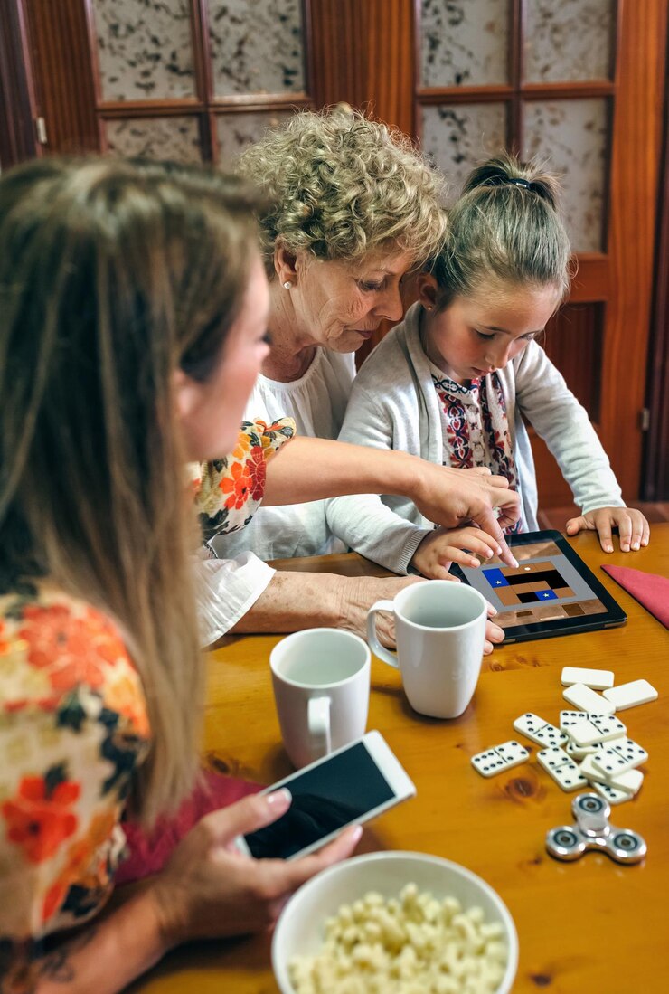 Foto avó e neta jogam um jogo no tablet enquanto a mãe assiste