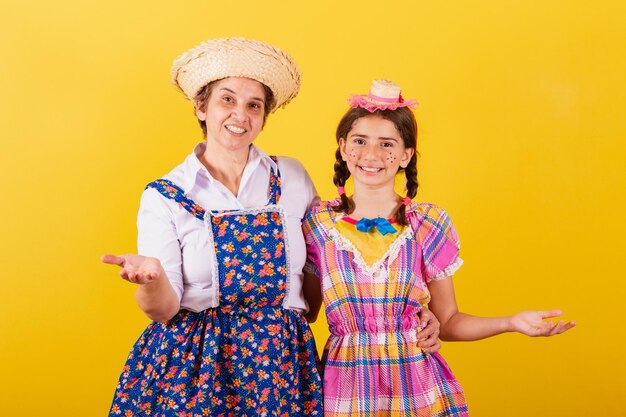 Avó e neta vestidas com roupas típicas da Festa Junina Bem-vindo convidando a sorrir