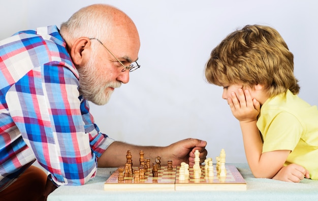 Avô e neto jogando xadrez. criança aprendendo a jogar xadrez. menino pensa ou planeja o jogo de xadrez. xeque-mate.