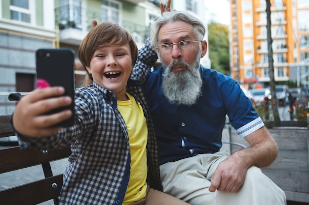 Avô e neto rindo tirando selfies no smartphone