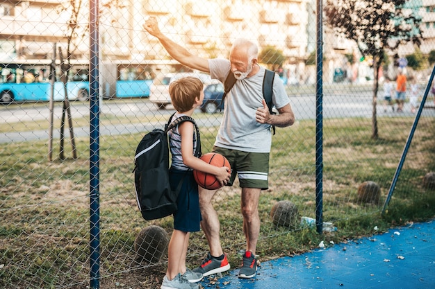 Avô e neto se divertindo juntos na quadra de basquete.