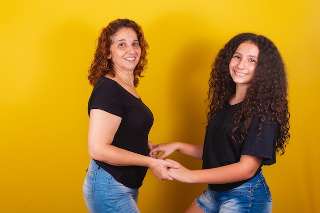 Foto avó e sobrinha brasileira latino-americana cachos cabelo afro encaracolado sorrindo mãos nos quadris família ph