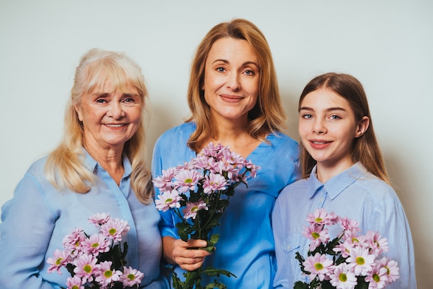 Avó, filha e neto juntos em casa segurando um ramo de flores