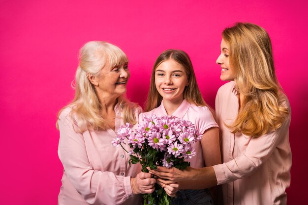 Avó, filha e neto juntos segurando um ramo de flores