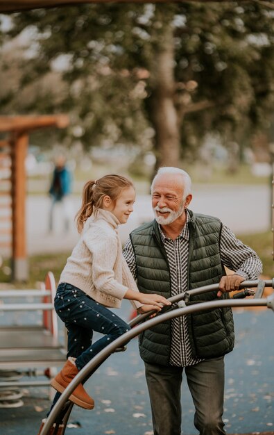 Avô passando tempo com sua neta no parque infantil no dia do outono