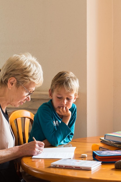 Avó que ensina em casa ensinando criança, criança, menino inteligente. família feliz, tempo juntos, ficar em casa, educação, estudar o conceito.