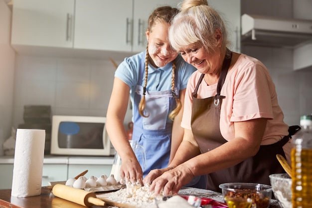 Avó satisfeita com a neta ajudando-a na cozinha