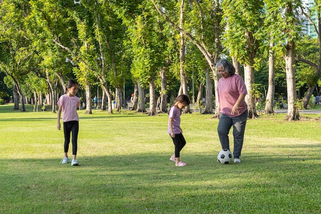 Avó saudável e feliz enquanto sua neta joga futebol no parque Conceito de avós passando tempo com menina