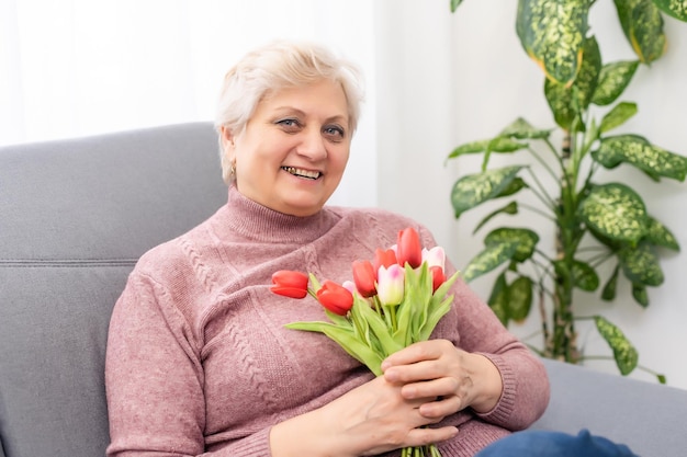 Avó segurando buquê de flores, sorrindo.