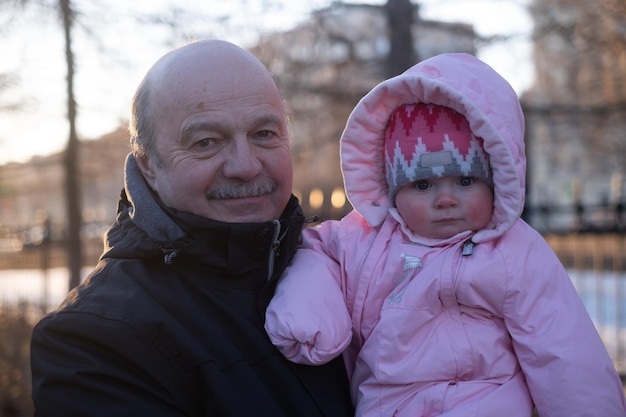 Avô sênior segurando sua neta sorrindo