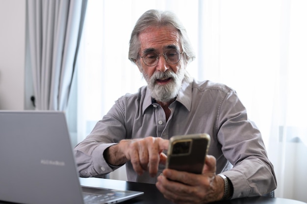 Avô sênior usando laptop e telefone inteligente em casa Felizes aposentados relaxando e descansando