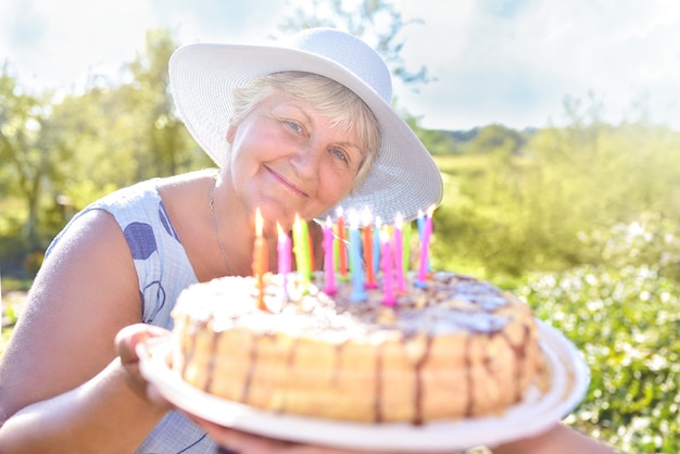 Avó sorridente segurando um bolo caseiro de aniversário. celebração de família