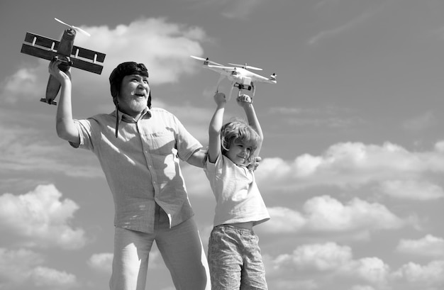Foto avô velho e neto criança jovem seguram avião e drone quad copter contra o céu piloto criança