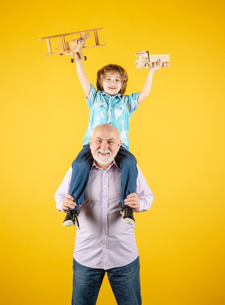 Avô velho e neto de criança com avião de brinquedo e caminhão de brinquedo de madeira Geração de homens avô e neto