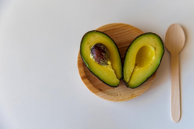 Avocado auf einem ökologischen Holzteller mit weißem Hintergrund Nahaufnahme Ein Herz aus zwei Avocado-Hälften Valentinstag Valentinstag