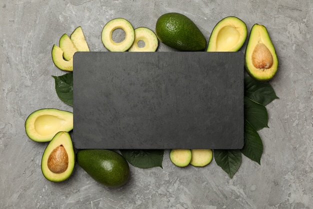 Foto avocado, blätter und tafel mit platz für text auf grauem hintergrund