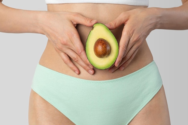 Avocado em mãos femininas no fundo do corpo Dieta de fertilidade da saúde das mulheres