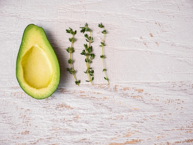 Avocado halbiert auf weißem Holzbrett.