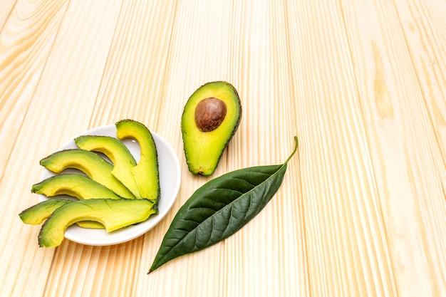 Avocado, halbiert, mit Knochen, Avocadoscheiben und Avocadoblatt