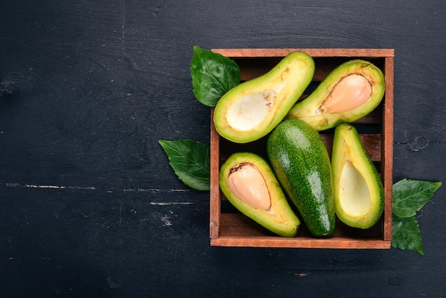 Avocado in einem hölzernen Korb Auf einem hölzernen Hintergrund Ansicht von oben Freier Platz für Ihren Text