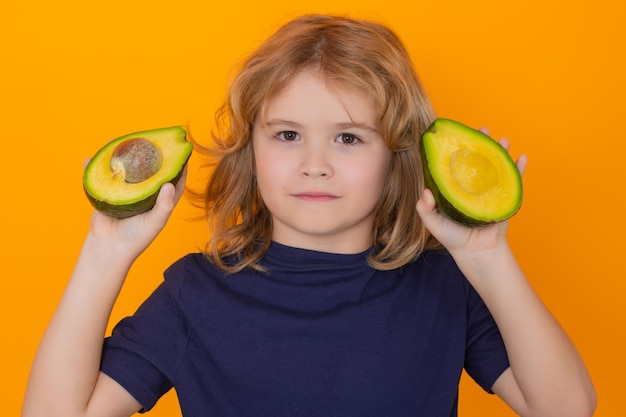 Avocado Kid sostiene aguacate rojo en el estudio Retrato de estudio de un niño lindo con aguacate aislado en un espacio de copia de fondo amarillo