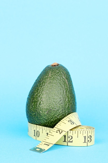 Avocado mit Maßband auf blauem Hintergrund