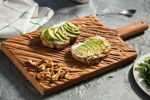 Avocado-Sandwich auf dunklem Roggenbrot mit frisch geschnittenen Avocados vom obigen Frühstückskonzept