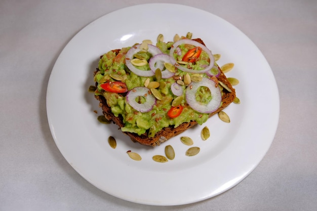 Avocado-Sandwiches Hälfte Avocado mit Erdnüssen und Kürbiskernen Zwiebelringe Paprika auf weißem Hintergrund