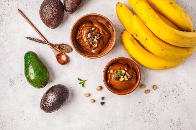 Avocado-Schokoladenmousse mit Pistazien in einer Holzschale auf einem weißen Hintergrund