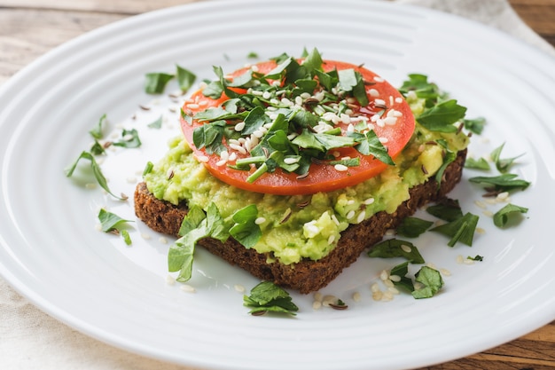 Avocado Toast. Gesunder Toast mit Avocadobrei und Tomaten auf einer Platte.