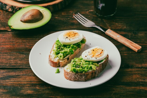 Foto avocado-toast mit frischkäse und gekochtem ei zum frühstück