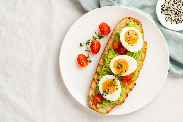 Avocado-Toast mit geröstetem Brot, weich gekochten Eiern mit Tomaten