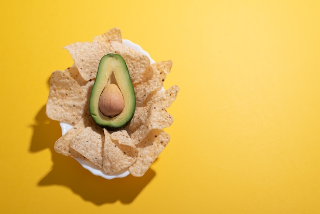 Avocado- und Nachos-Teller flach als Guacamole-Konzept auf einem einfachen, lebendigen Schreibtisch