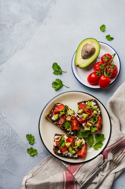 Avocados, Kirschtomaten und Feta-Käse-Sandwiches mit Balsamico-Sauce und Koriander. Draufsicht.