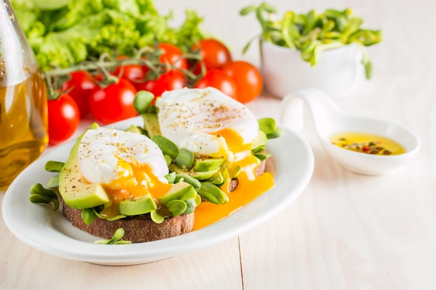 Avocadotoast, Kirschtomate und poschierte Eier auf hölzernem Hintergrund.