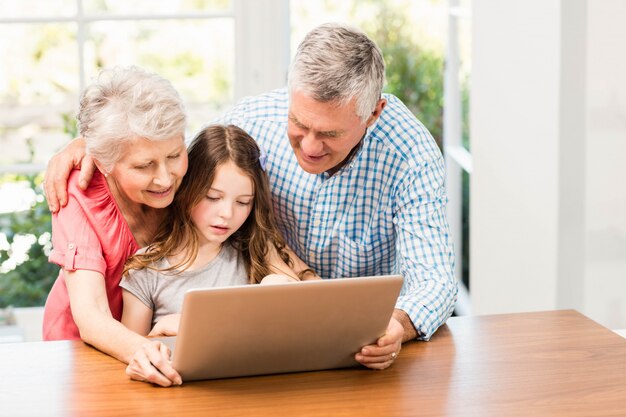 Avós e neta usando laptop em casa