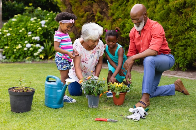 Avós e netos afro-americanos regando plantas no jardim