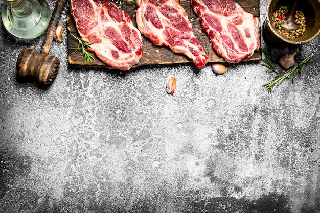 Aw Fleisch Hintergrund. Rohes Schweinefleisch mit Gewürzen und Kräutern. Auf einem rustikalen Tisch.