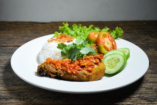 Ayam geprek comida indonesia o pollo geprek con salsa picante de sambal servido con arroz en un plato blanco