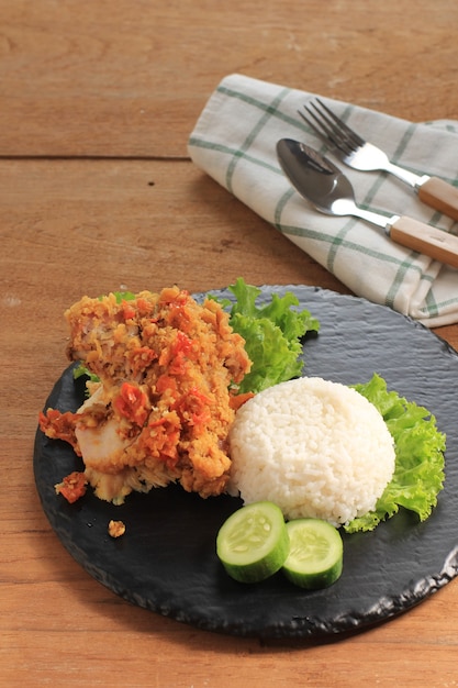 Ayam Geprek ist beliebtes Streetfood in Indonesien. Hergestellt aus knusprigem Hühnchen, das in Sambal Bawang (Chili-Knoblauch-Sauce) zertrümmert wird. Serviert mit Reis und Gemüse