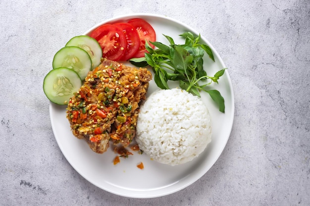 Foto ayam geprek wird aus knusprigem hühnchen zubereitet, das in sambal-bawang-chili-knoblauch-sauce zerdrückt wird